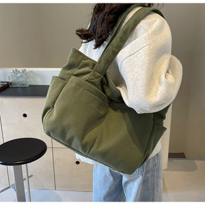 Detail of army green corduroy tote bag with multiple pockets shown on model shoulder