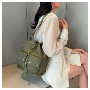 Detail of army green nylon drawstring bucket bag with double front pockets and metal buckles
