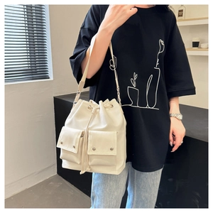 Close-up of minimalist beige nylon bucket bag with drawstring closure and two front pockets
