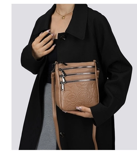 Detail of brown leather crossbody bag with embossed rose pattern and triple zipper pockets