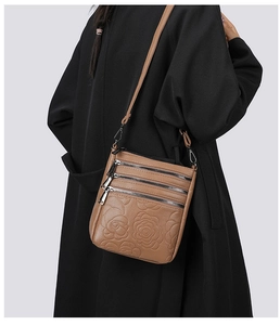 Detail of brown leather bucket bag with embossed roses and triple zipper pockets
