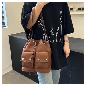 Close-up of brown nylon drawstring bucket bag with flap pockets and wide shoulder strap