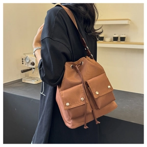 Detail of a brown nylon bucket bag featuring drawstring closure and two front pockets