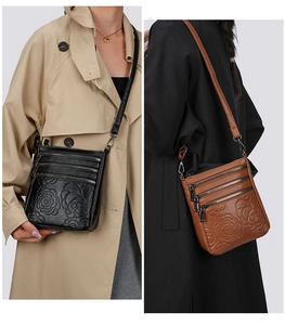 Detail view of women's bucket bag with embossed rose pattern and multi-zipper pockets