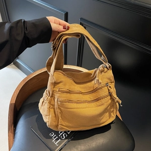 Mustard yellow canvas tote bag with multiple zipper compartments shown on a chair