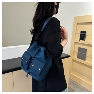 Detail of dark blue nylon bucket bag showing drawstring closure and front flap pockets