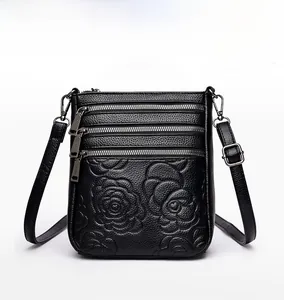 Detailed front view of black pebbled leather crossbody bag with rose embossing