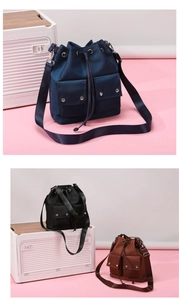 Detail view of nylon bucket bags in navy, black and brown with drawstring closure