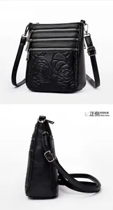 Close-up of black lychee leather crossbody bag with rose embossing and multiple zippers