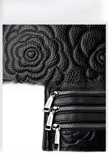 Close-up of embossed floral leather texture and premium silver zipper on women's handbag