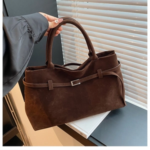 Close-up of brown suede tote bag with decorative strap and square silver metal buckle
