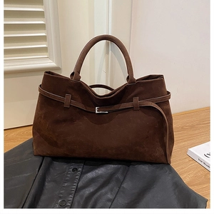 Detail of dark brown faux suede tote bag with belt buckle accent and leather texture
