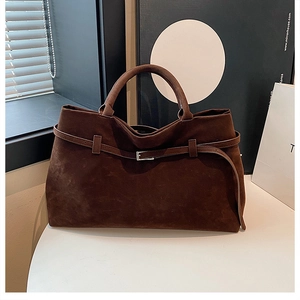 Detailed macro view of the brown suede tote bag featuring decorative belt buckle hardware