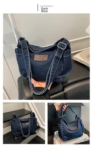 Detail view of dark blue denim tote bag with brown leather logo and adjustable strap