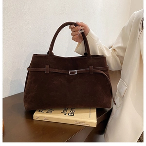 Detail of dark brown faux suede tote bag with decorative belt and silver buckle