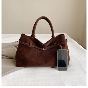Detailed close-up of brown suede tote bag with decorative leather belt and silver buckle