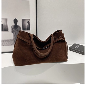 Detail of a brown suede tote bag with decorative strap and minimalist stitching
