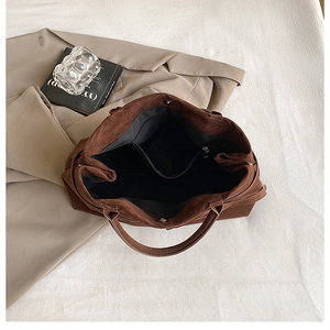 Deep brown tote bag detail showing spacious interior, magnetic buckle and inner zipper pocket