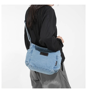 Macro shot of blue denim shoulder bag featuring a vintage leather patch and metal buckle