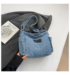 Close-up of retro denim crossbody bag featuring brand leather patch and adjustable strap