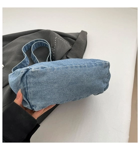 Detail of washed blue denim shoulder bag showing vintage texture and durable wide strap