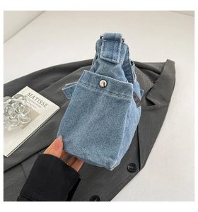 Detail of light blue denim tote bag with side pocket and silver snap button closure