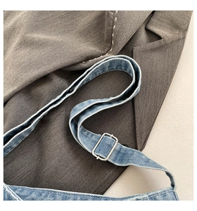 Detail of adjustable blue denim strap with silver metal buckle on shoulder bag