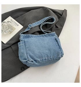 Detail of adjustable metal buckle on light blue denim shoulder bag with side pocket feature