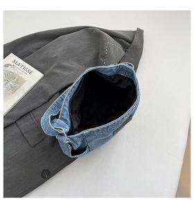 Detail view of denim tote bag showing zipper closure, black lining and leather patch