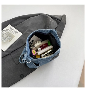 Internal view of a spacious washed denim shoulder bag with multi-item storage capacity
