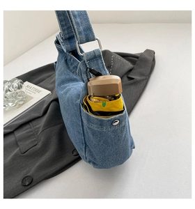 Detail of light blue denim shoulder bag with a functional side pocket and yellow umbrella