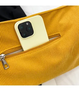 Close-up of yellow corduroy tote bag detail featuring a functional side zipper pocket