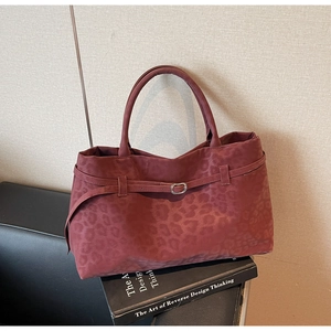 Detail of burgundy leopard print suede tote bag with metallic buckle and soft matte texture