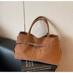 Detail einer braunen Wildleder-Tragetasche mit Leopardenmuster und silberner Schnalle