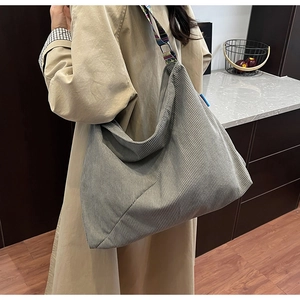 Gray corduroy tote bag with jacquard strap worn with a beige trench coat