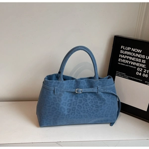 Detail of blue suede tote bag featuring leopard print texture and metal buckle handle