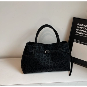 Close-up of black leopard pattern tote bag with leather straps and silver metal buckle