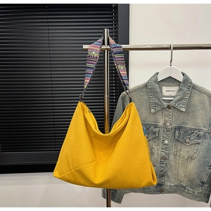 Detail view of yellow corduroy tote bag with ethnic print strap on a hanger