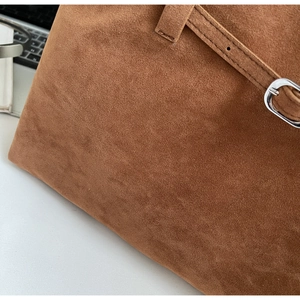 Detailed macro view of the brown suede tote bag with silver buckle and fine stitching