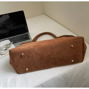 Detail view of brown suede tote bag base with four silver metal protective feet