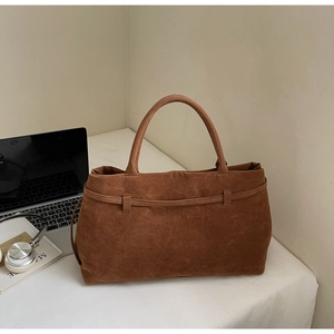 Detailed view of brown suede tote bag in office setting with laptop and accessories