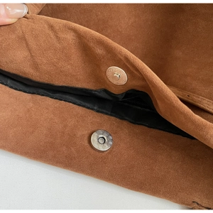 Macro detail of brown suede tote bag featuring a secure magnetic closure and black lining