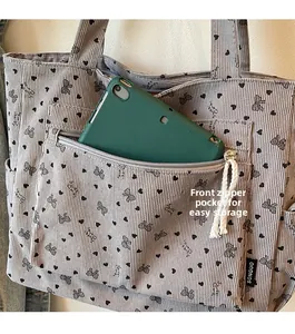 Corduroy tote bag featuring a front zipper pocket storing a green tablet device