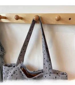 Detail of comfortable shoulder straps on gray corduroy tote bag with bow print
