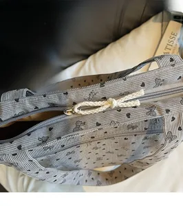 Close-up of the smooth metal zipper and white woven puller on the corduroy tote bag