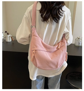 Vue de dos du sac demi-lune en velours côtelé rose avec un nœud tressé décoratif au zip