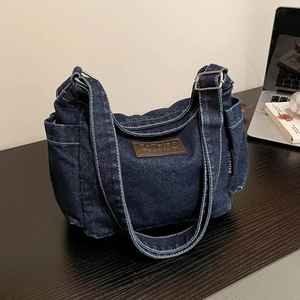 Retro deep blue denim crossbody bag with adjustable strap on a dark wooden desk