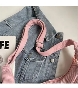 Détail d'un sac demi-lune en velours côtelé rose avec bandoulière réglable et boucle en métal