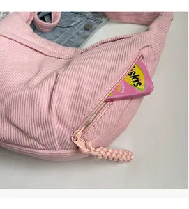 Vue détaillée du sac croissant en velours côtelé rose avec poche latérale zippée