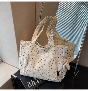 Detail of white corduroy tote bag showing heart bow prints and front zipper pocket